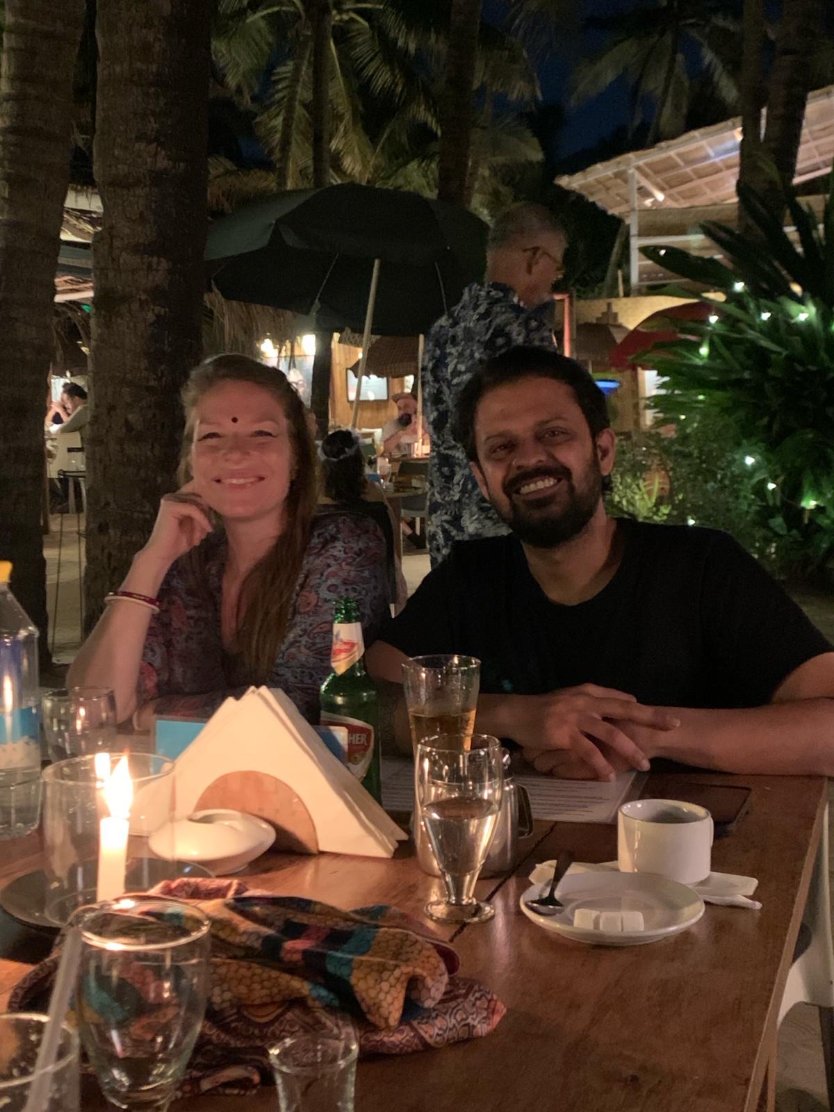 Veer et Jyoti souriants, en soirée, autour d'une table.
