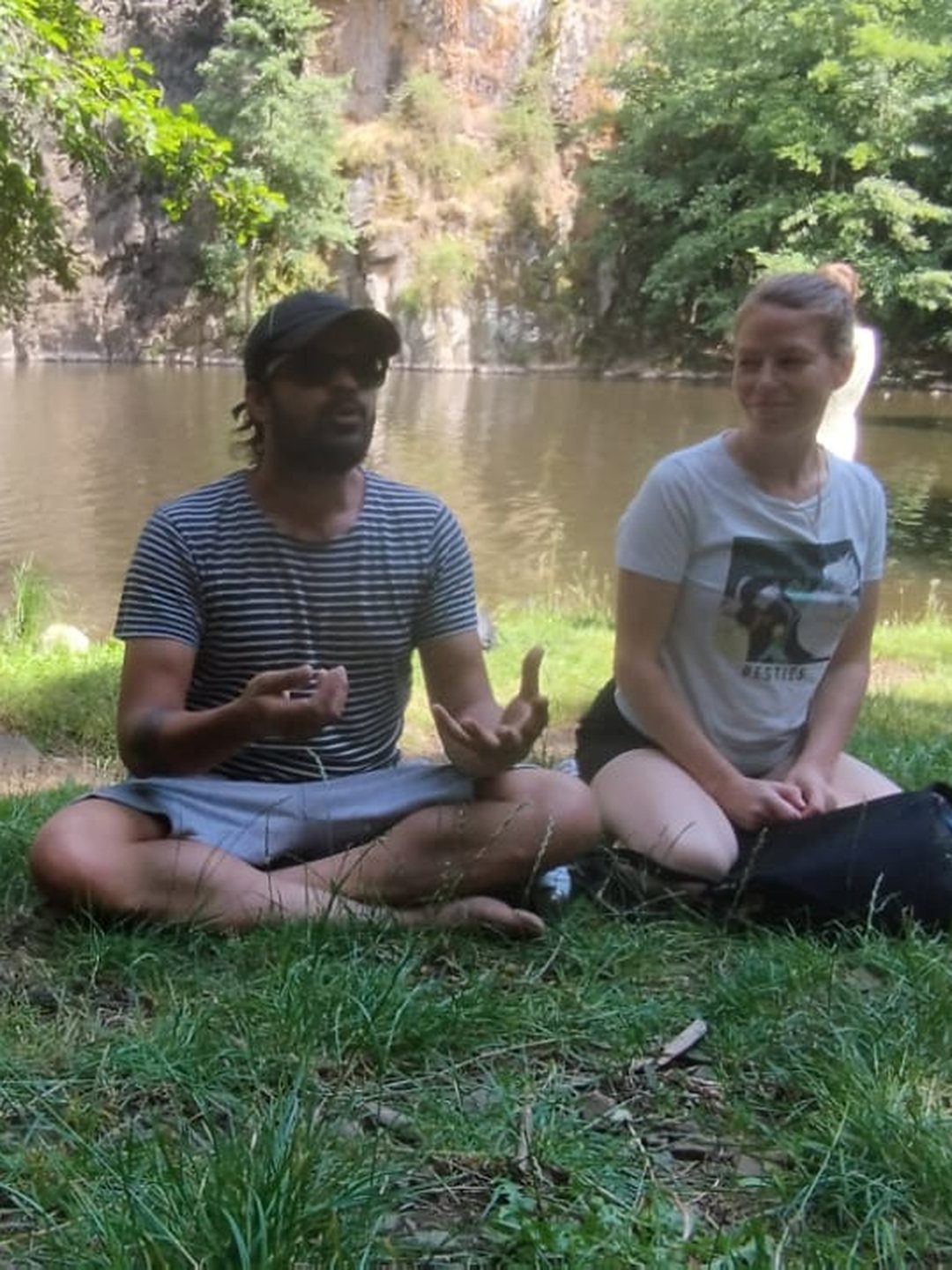Veer et Jyoti Anand, enseignants d'Adinatha Yoga, assis côte à côte au bord d'une rivière : leurs deux visages sont tournés l'un vers l'autre dans un moment d'échange calme.